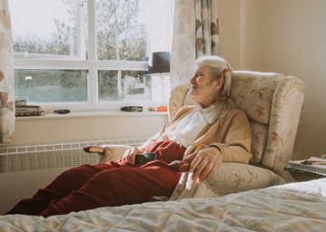 Elderly person in a chair looking out the window
