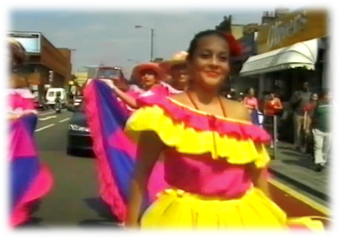 Carnival goers, in colourful clothes, dancing along Walworth Road