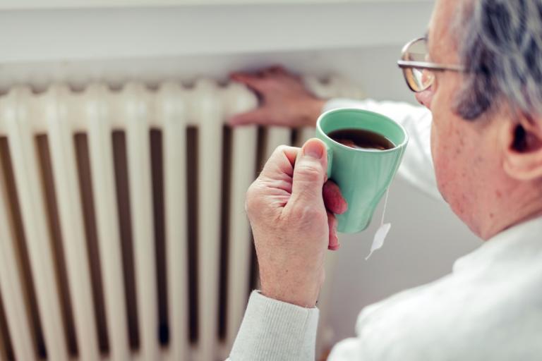 Pensioner checking the heating while having a cup of tea