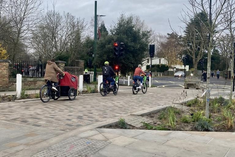 Cyclists travelling through Dulwich Village past new widened pavements and landscaping