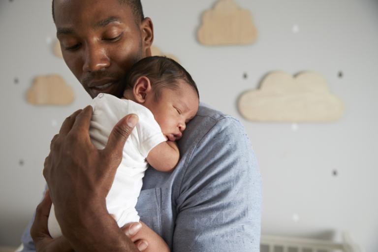 Father holding newborn baby in nursery