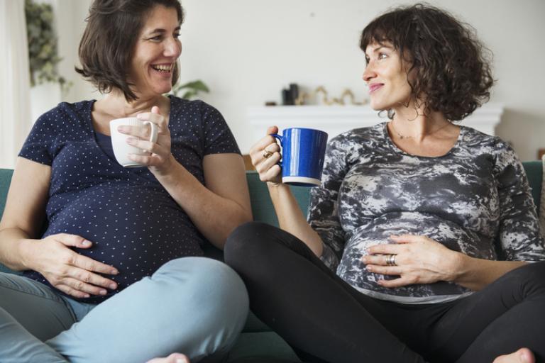 Two pregnant women talking and drinking coffee
