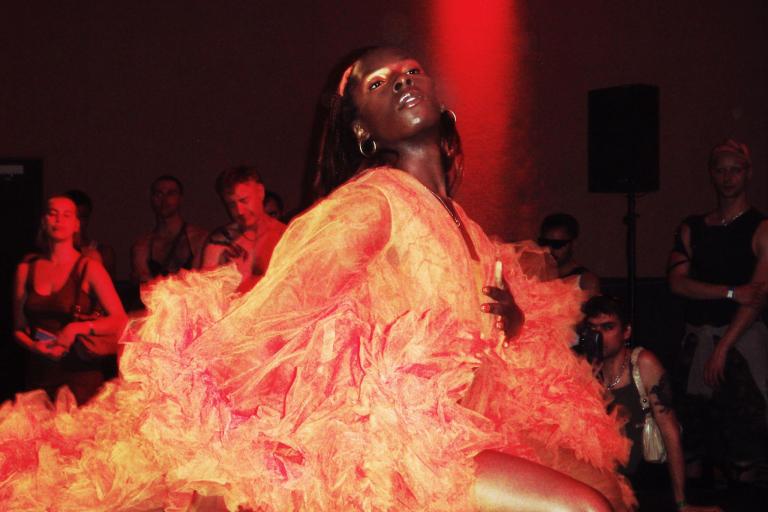 Artist Chloe Filani performs wearing a bright orange dress.