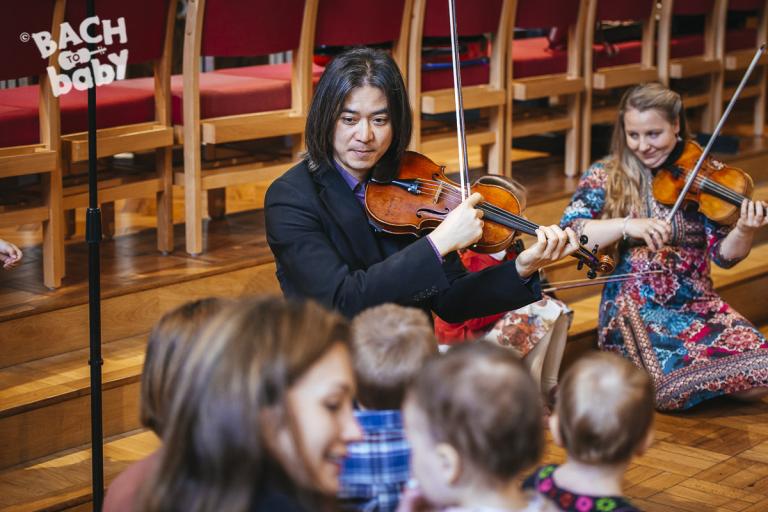 violinists play to interested toddlers