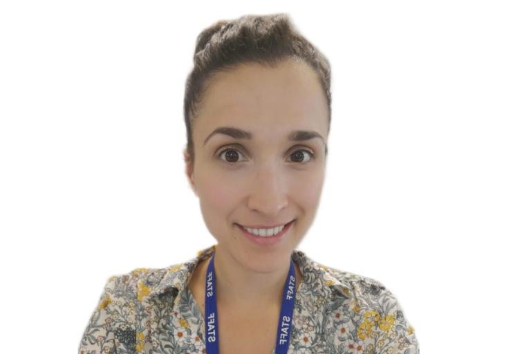 A woman with dark brown hair tied back, wearing a floral patterned shirt