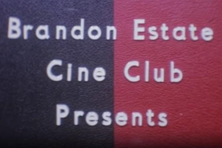 Screenshot of an intertitle reading 'Brandon Estate Cine Club Presents' from the film Return to Canvey Island (1972). White letters on dark blue and maroon coloured background.