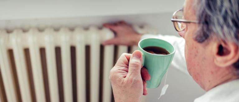 Pensioner checking the heating while having a cup of tea