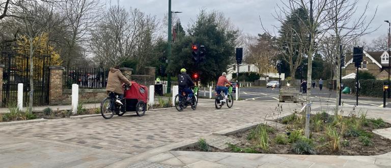 Cyclists travelling through Dulwich Village past new widened pavements and landscaping