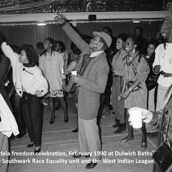A group of Black people in an event hall (Dulwich Baths), smiling and celebrating