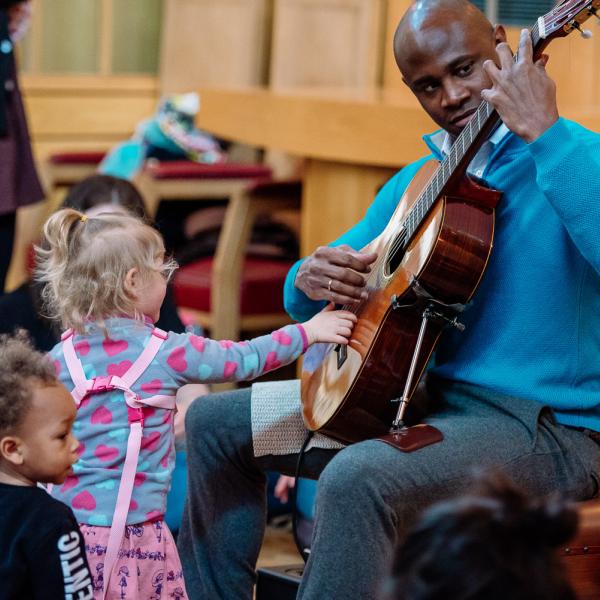 child investigates bach to baby guitarist