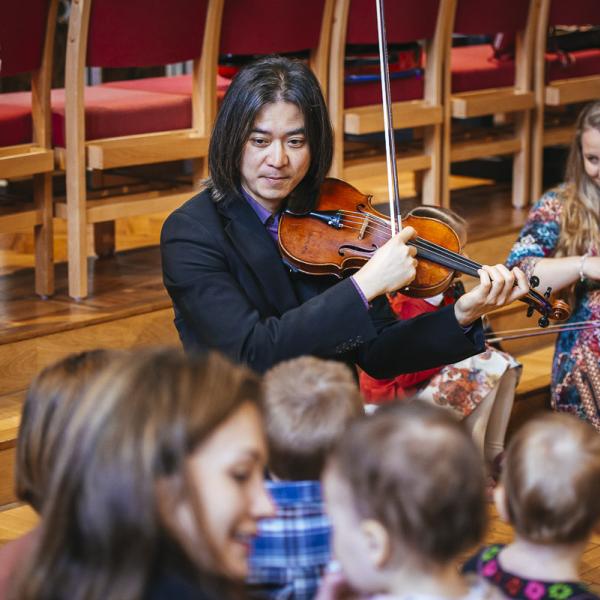 violinists play to interested toddlers