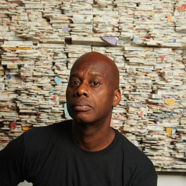 Artist Leonardo Drew sits in front of one of his works of art.