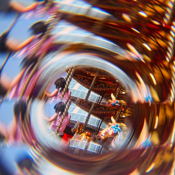 A blurry, kaleidoscopic style photo of a figure wearing pink on a fairground carousel
