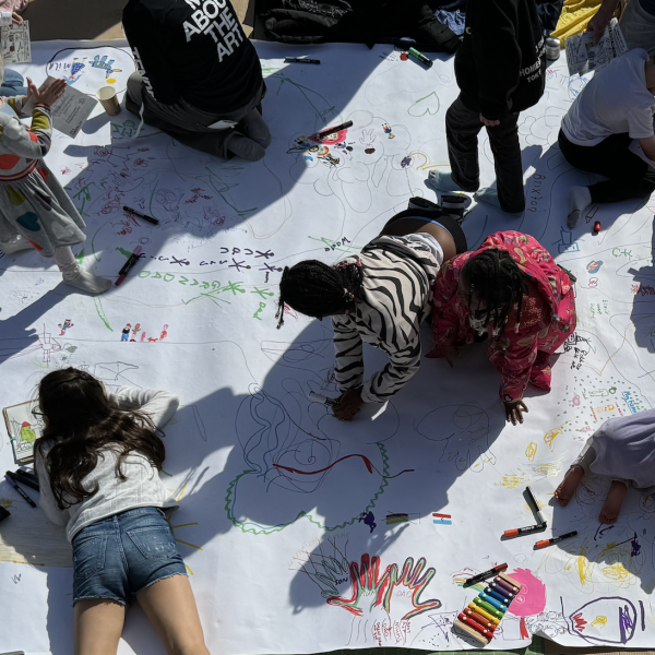 Birdseye view of children drawing on a large piece of paper on the floor