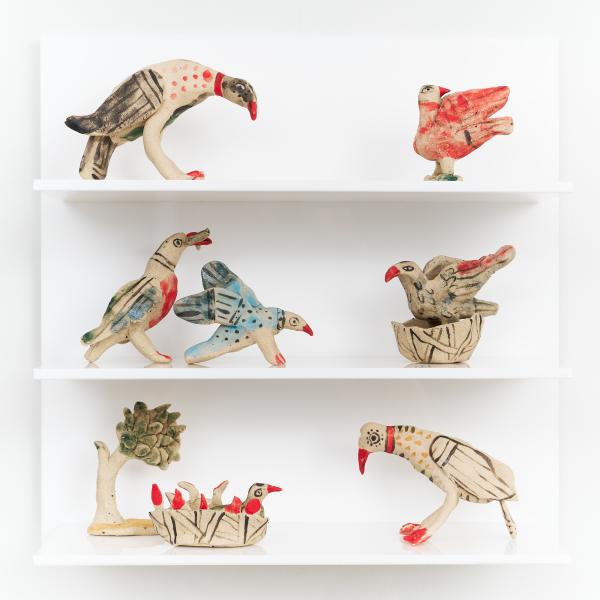 3 white shelves on a white background, each with two small ceramic birds sat on them